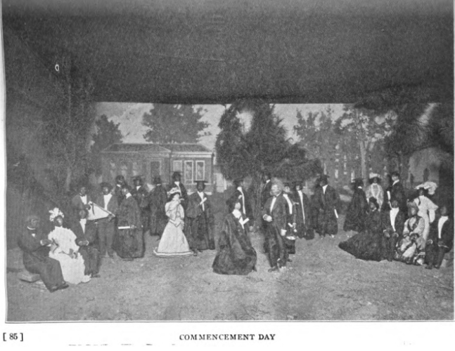 Photo of a diorama of miniature persons formally dressed for "Commencement Day."