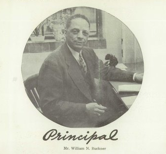 Photo of a man sitting at a desk holding a pen