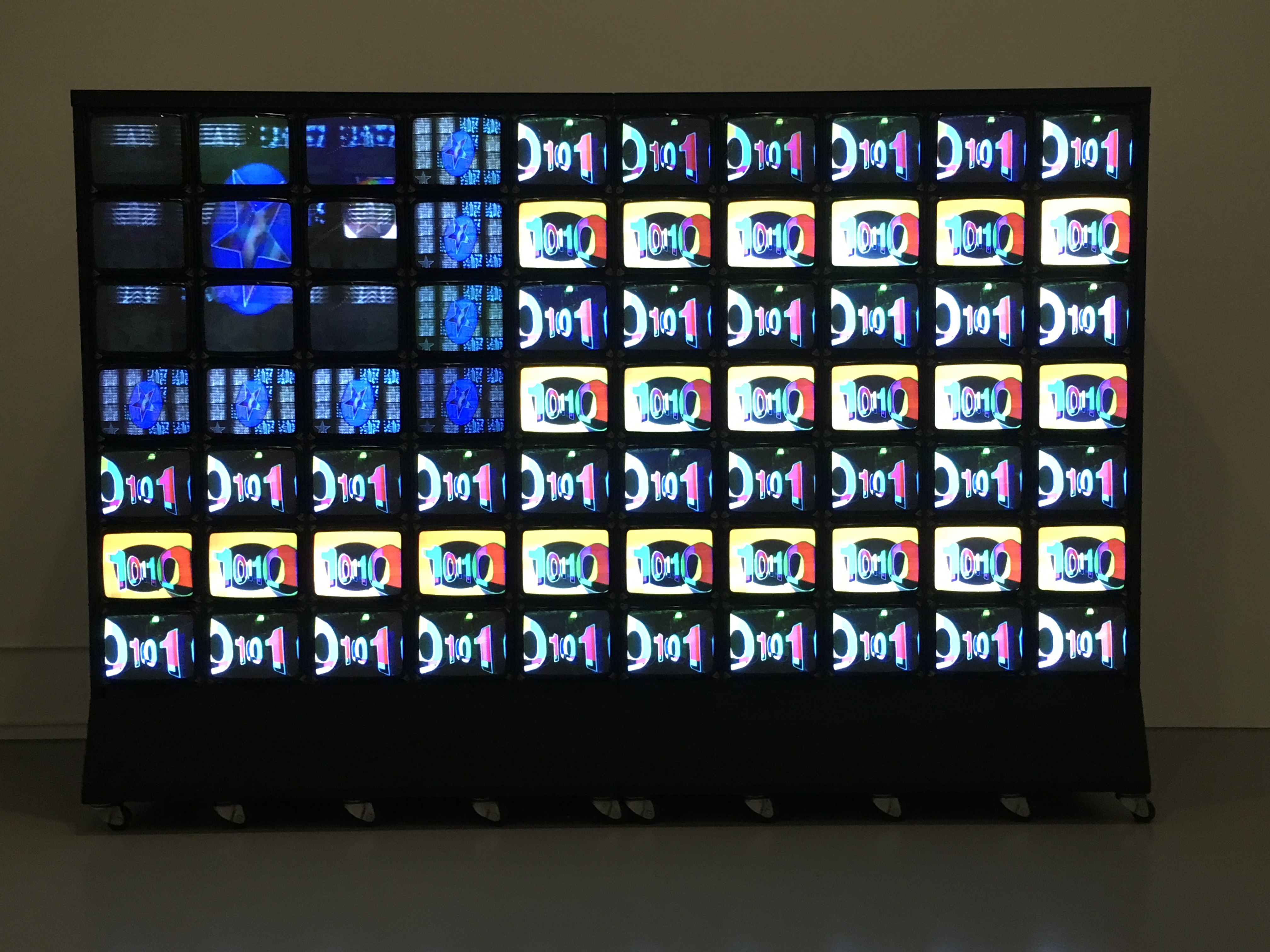 Rectangular wall of stacked video monitors displaying artwork