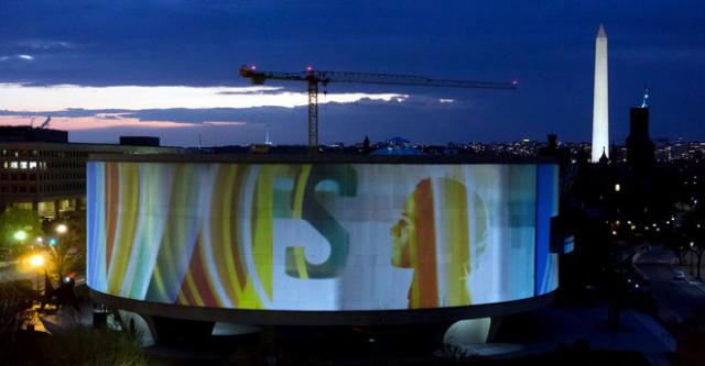 "SONG 1" artwork projected on to the Hirshhorn Museum at night.