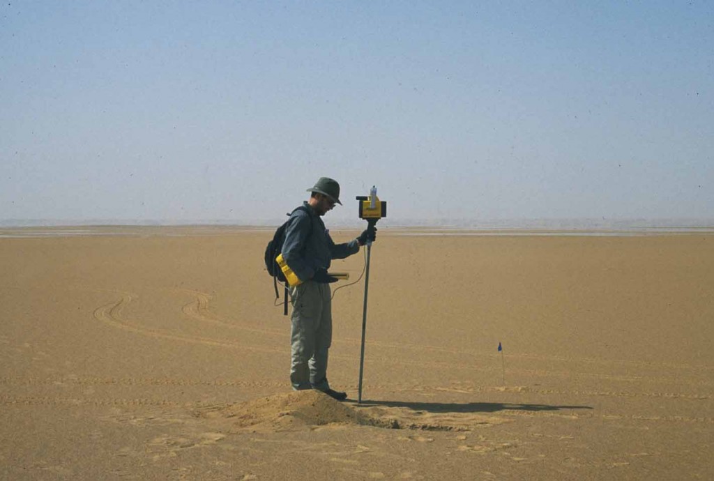 Geologist standing in a desert with a GPS device