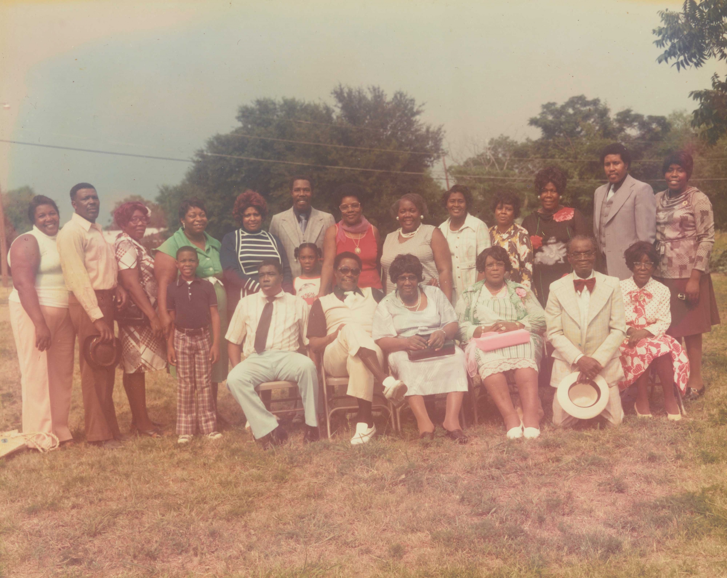 A group of women, men and children outside on the grass. 