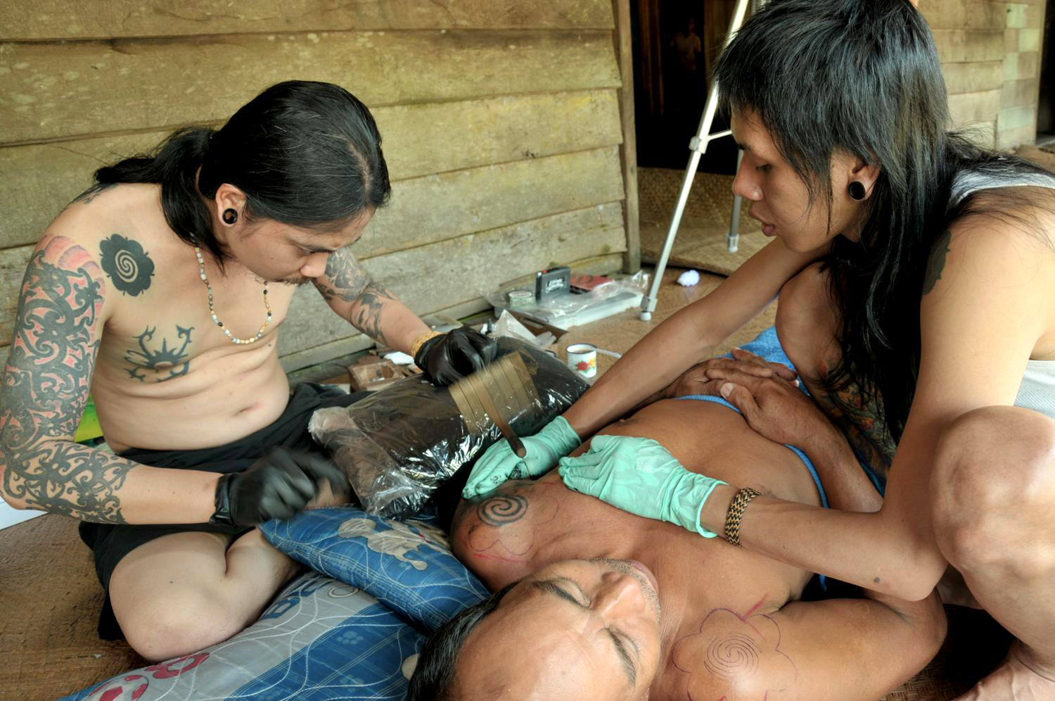 Iban tattooist Herpianto Hendra and his assistant Erzane NE hand-tapping an elder on the Kapuas River, Kalimantan. (Image copyright © Herpianto Hendra)