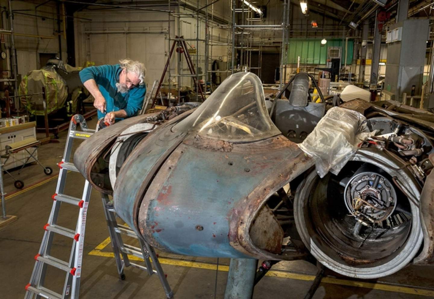 mechanic on ladder repairing aircraft