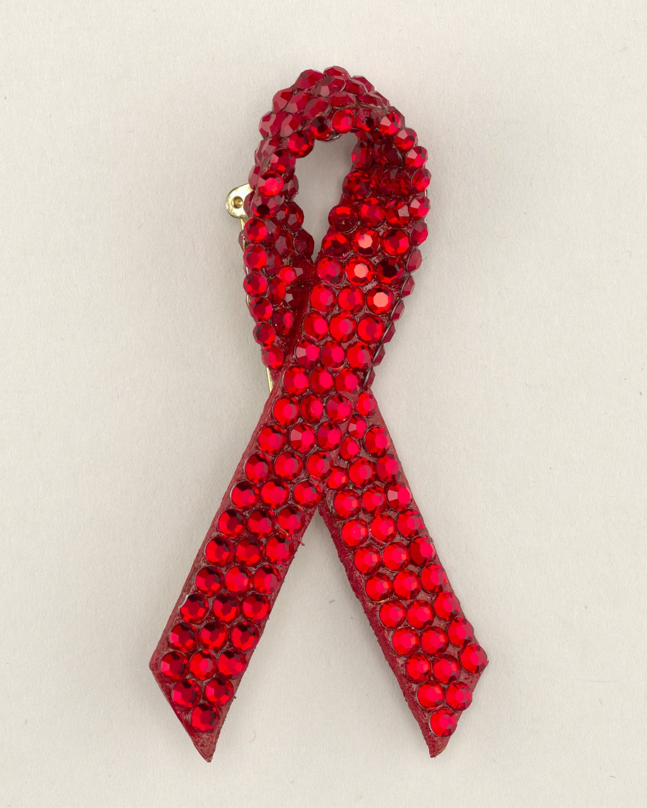 Jeweled pin in the shape of a looped red ribbon.