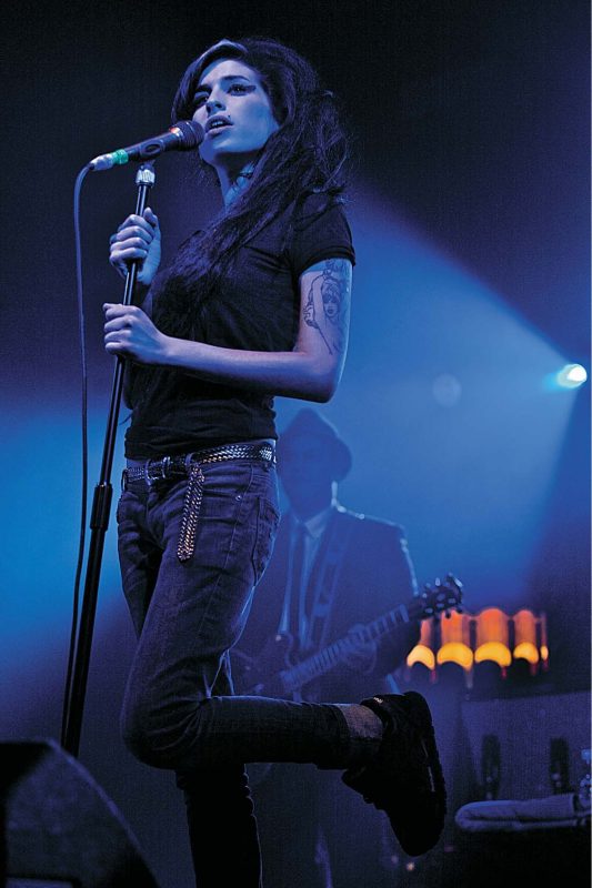 Amy Winehouse singing at a microphone.