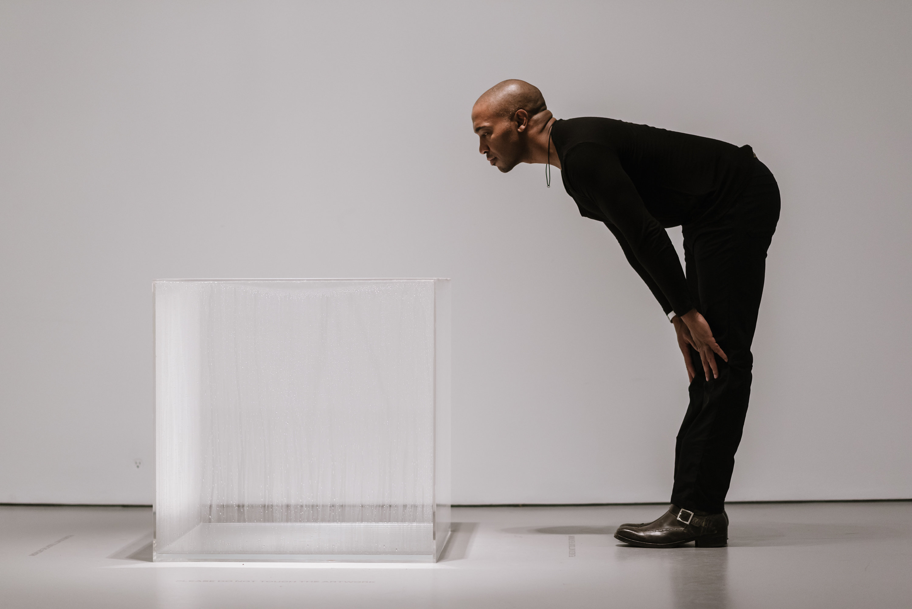 Man leaning over to look at a clear cube