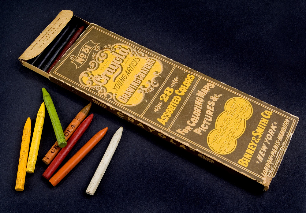 Brown and yellow box of Crayola young artist drawing crayons with a handful of crayons next to it