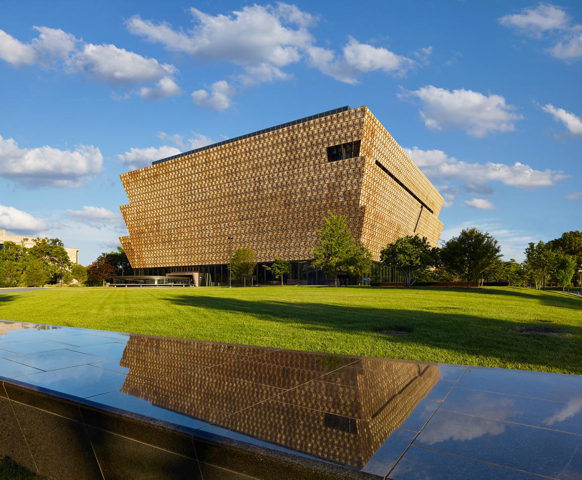 Exterior of National Museum of African American History and Culture with clear blue skies and a reflecting pool