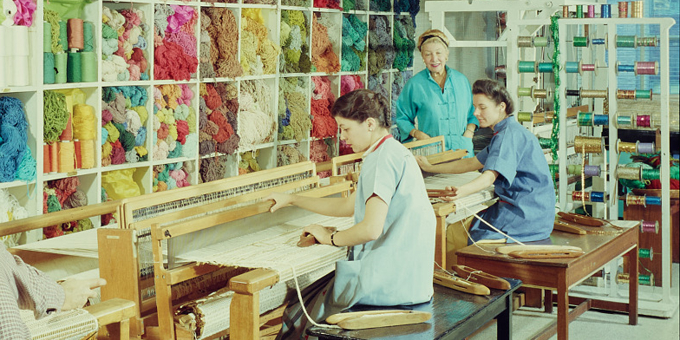 Two women work in front of a textile loom