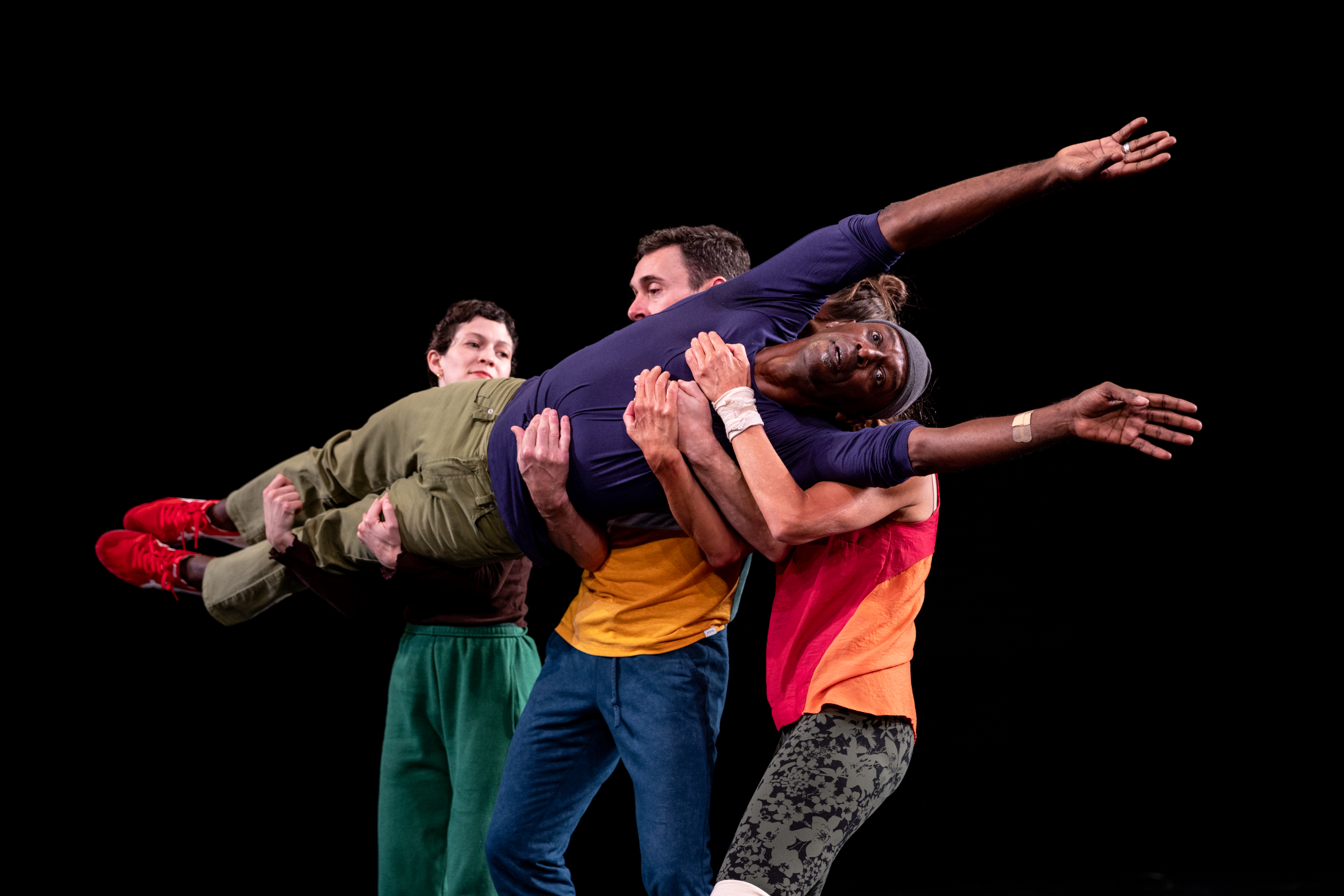 Three people carry a fourth person laying straight across in their arms