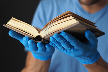 Hands holding book with glove
