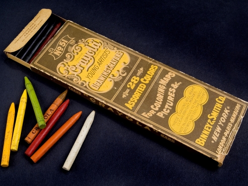 Brown and yellow box of Crayola young artist drawing crayons with a handful of crayons next to it