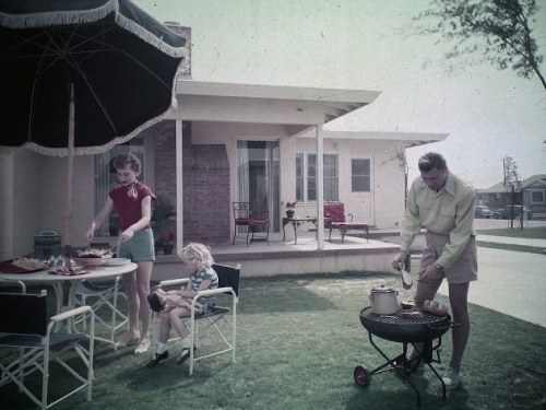 backyard with man grilling and woman at outdoor dining table