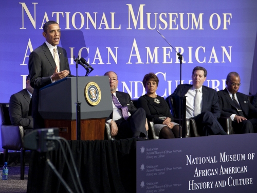 President Barack Obama speaks at podium in front of National Museum of African American History and Culture