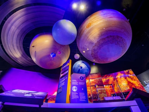 Brightly lit sculptures of planets inside museum exhibit