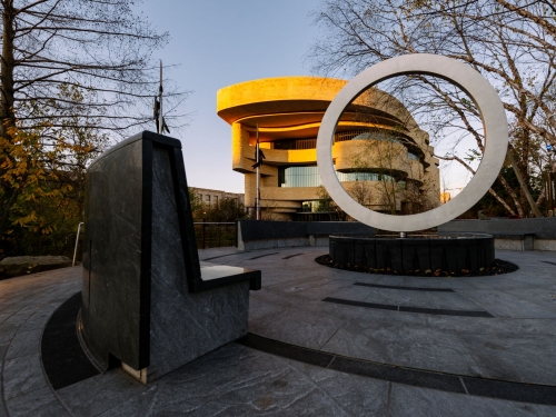 Sculptural memorial seen outside National Museum of the American Indian at sunrise
