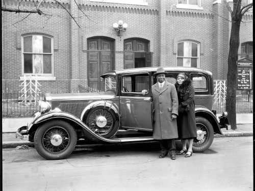 Couple stands next to old sedan
