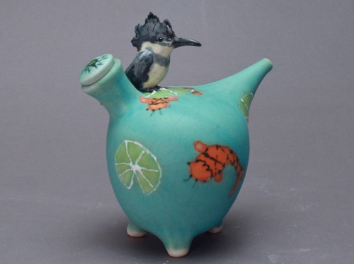 Turquoise ceramic with small orange koi fish and lime slices painted on side, small ceramic bird on top.