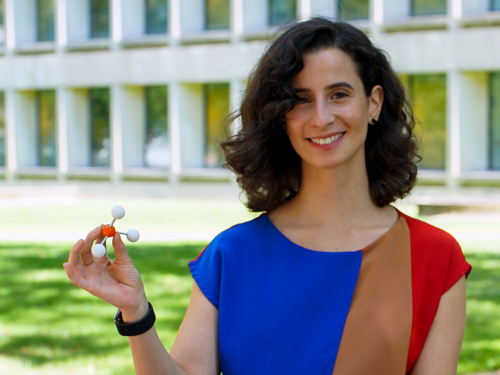 Woman holds a molecular model while standing outside