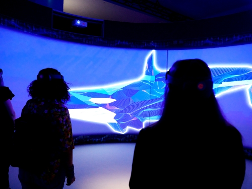 People watch video screen displaying an orca illustration