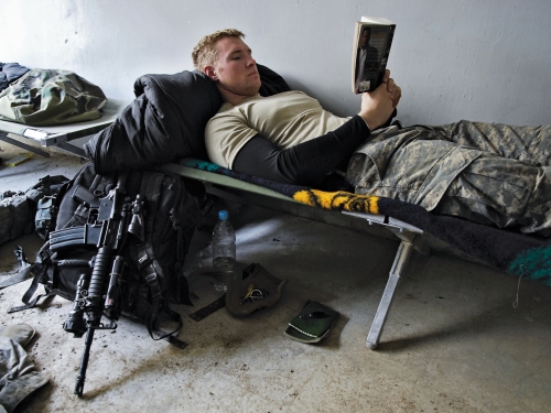 soldier reading while lying on cot