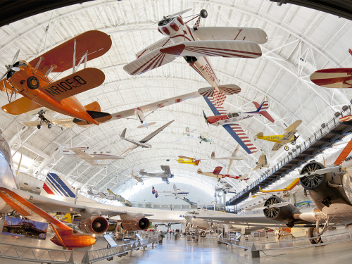 Panorama of indoor hangar with planes of various sizes and colors