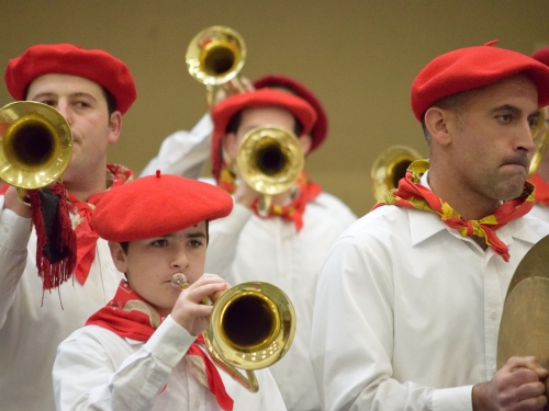 Boys and men wearing red berets and plating trumpets