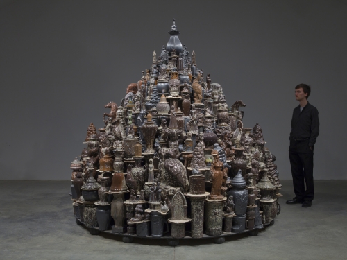 Artist standing next to his work, a sculpture comprised of china dishes