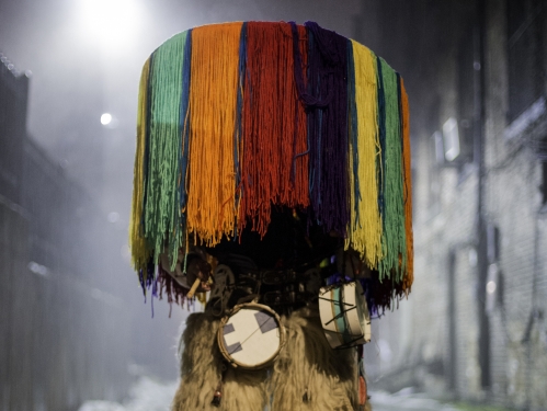 Person standing on city street completely obscured by colorful native costume