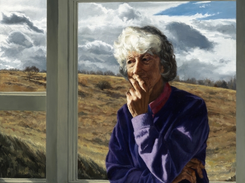 Woman with white bob and purple sweatshirt sits, crossing her arms, in front of a window overlooking an open field.