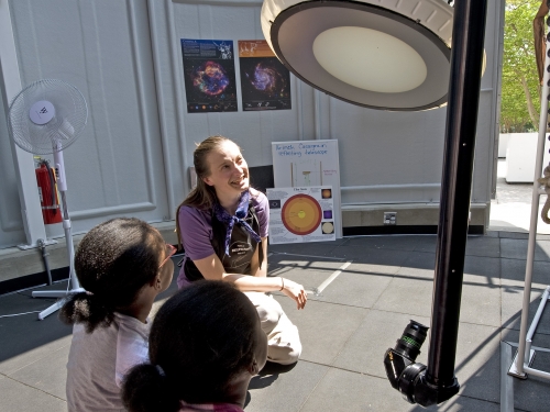 Children listen as woman explains telescope