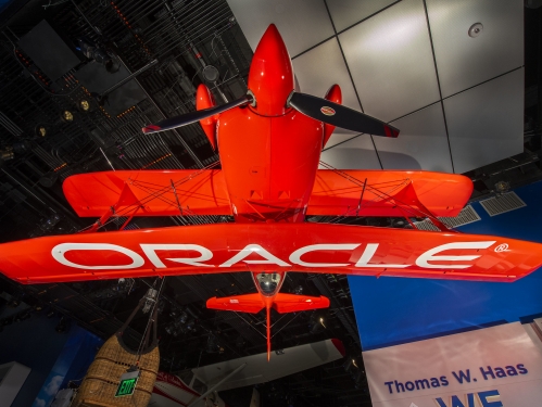 Bright red airplane with "Oracle" written on wings, hanging upside down