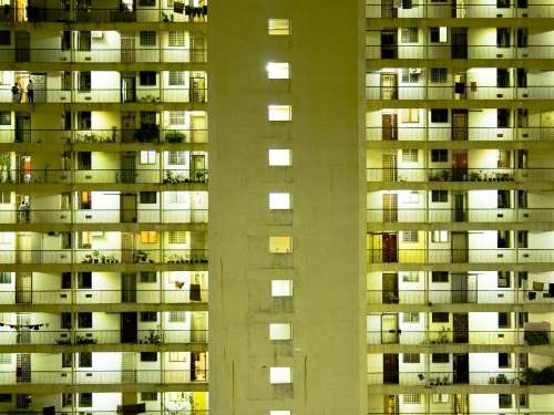 View of large apartment building exterior lit up at night