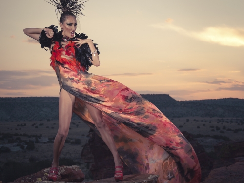 Woman in gown and dramatic makeup posed in desert