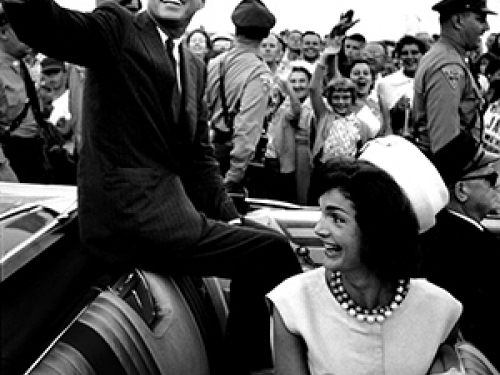 JFK waving from open convertible