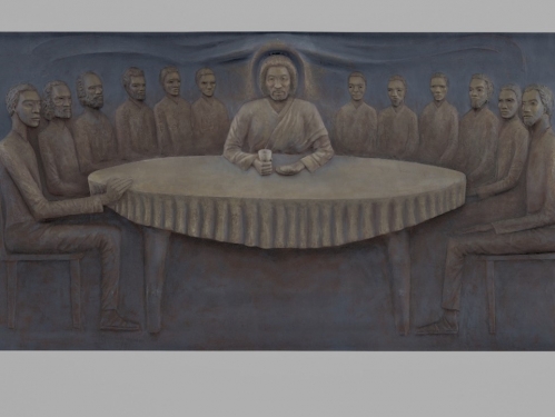 Relief sculpture of group of men sitting around table, one in center projects more from surface and has a halo and holds a cup.