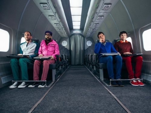 Four OK Go band members sitting in airplane seats