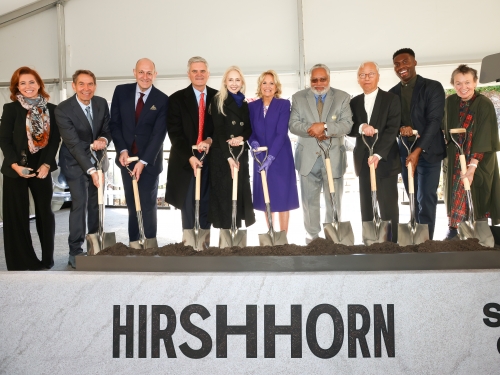 Group of people each pose with shovels in their hands, smiling ahead