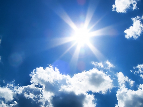 image of sun in a blue sky with white clouds