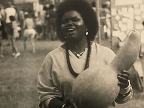 Woman singing and banging a gourd drum