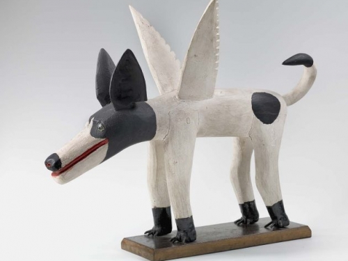 carved wooden dog with a black head, white body, and wings.