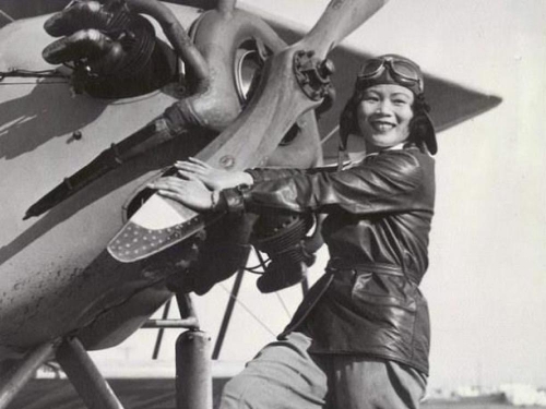 A woman stands in front of a propeller.