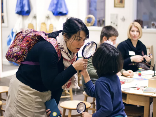 A mother looks at her child through a magnifying glass during a Family Program at the museum.