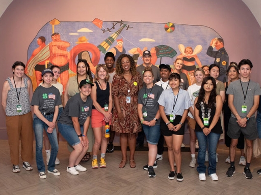 Under Secretary Dr. Monique Chism stands with a group of students in front of a museum artwork.