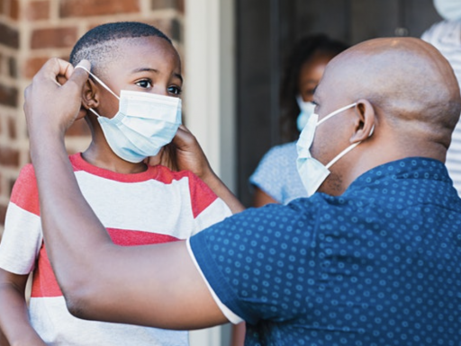 child being assisted with mask by an adult