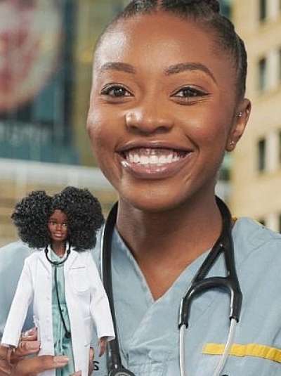 Woman in scrubs holding a Barbie doll.