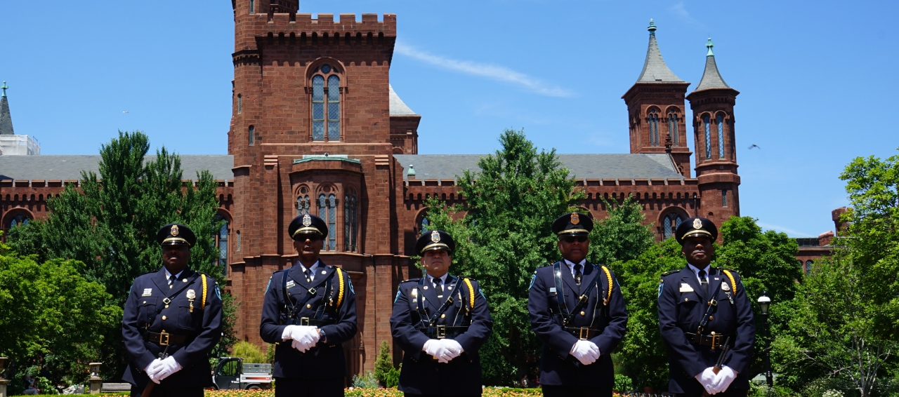Smithsonian OPS guards, in uniform, standing in front of the Smithsonian.