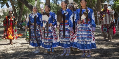A group of Native American women dressed as warriors in blue. 
