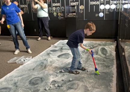 Child playing on model of moon's surface